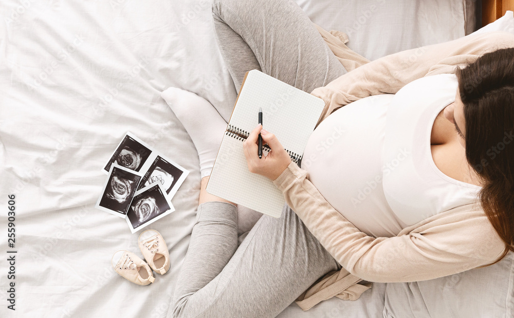 Pregnant woman making packing list for maternity hospital - obrazy, fototapety, plakaty 