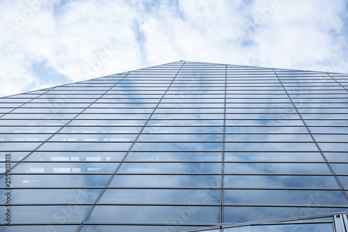 Cloud and sky reflected in the blue glass windows of building.