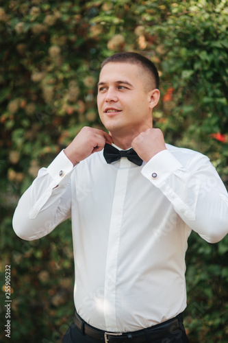 Young man walking in the park. Handsome groom in whitr shirt photo