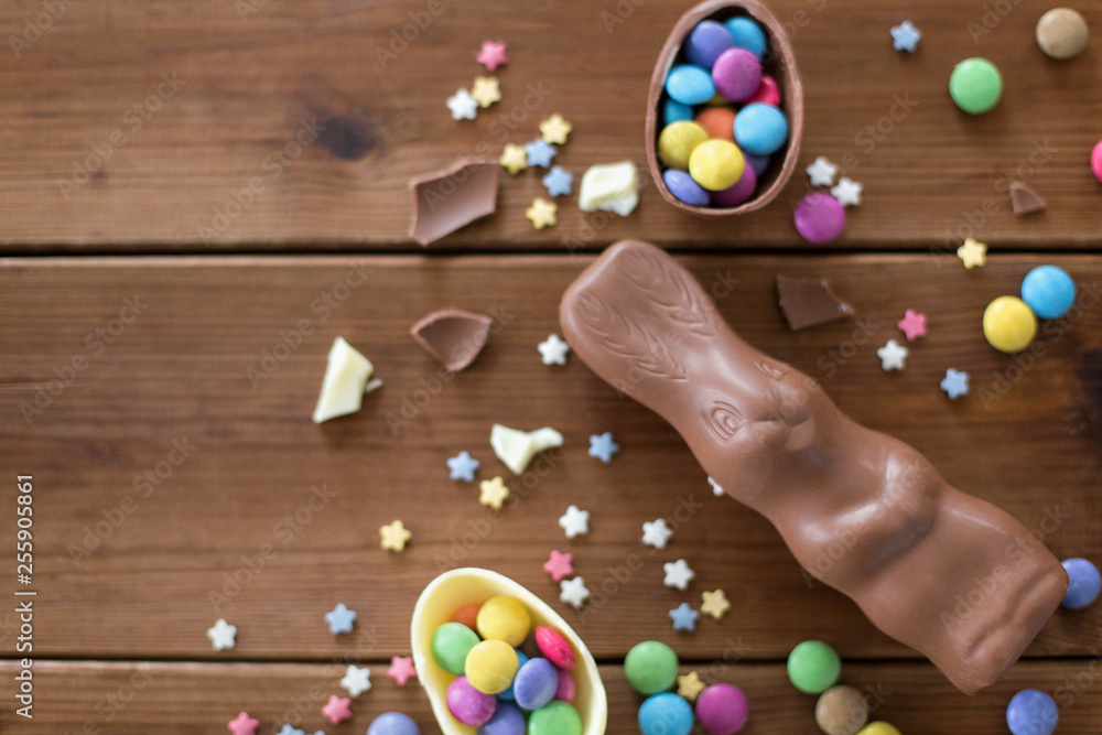 easter, sweets and confectionery concept - chocolate eggs, bunny and candy drops on wooden background easter, sweets and confectionery concept - chocolate eggs, bunny and candy drops on wooden background