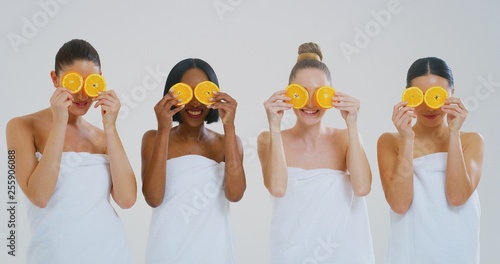 Canvas Print Portrait of beautiful young women of different ethnicities with perfect faces with eyes covered with kiwi slices smiling in camera isolated on a white background