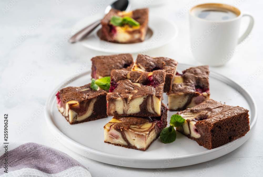 Cheesecake brownies with raspberry stacked on a white plate. Cheesecake brownies with raspberry stacked on a white plate.