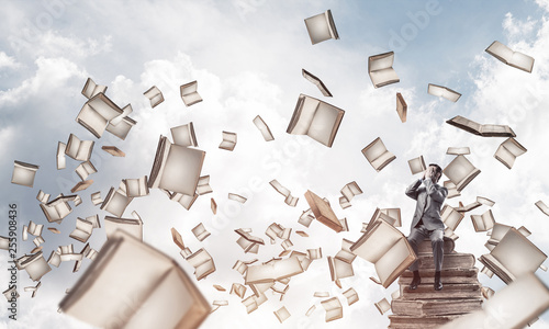 Young man sitting on books and do not want to see anything
