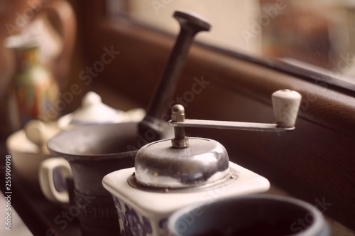 ręczny młynek do kawy i stary miedziany moździerz stojące pod oknem w kuchni