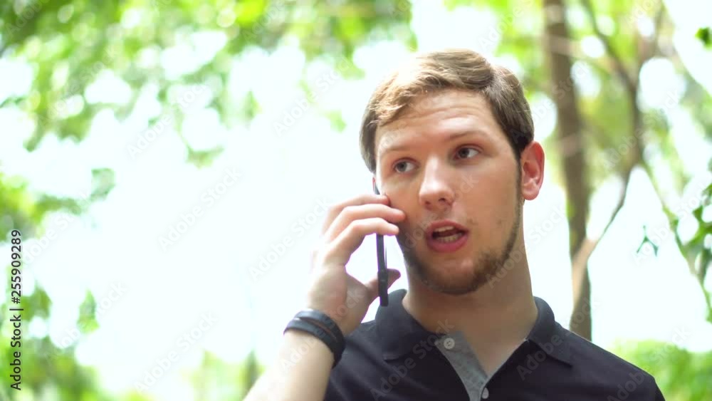 Portrait of Young Expressionate Caucasian Man Walking and Talking on Phone in Nature Setting Portrait of Young Expressionate Caucasian Man Walking and Talking on Phone in Nature Setting