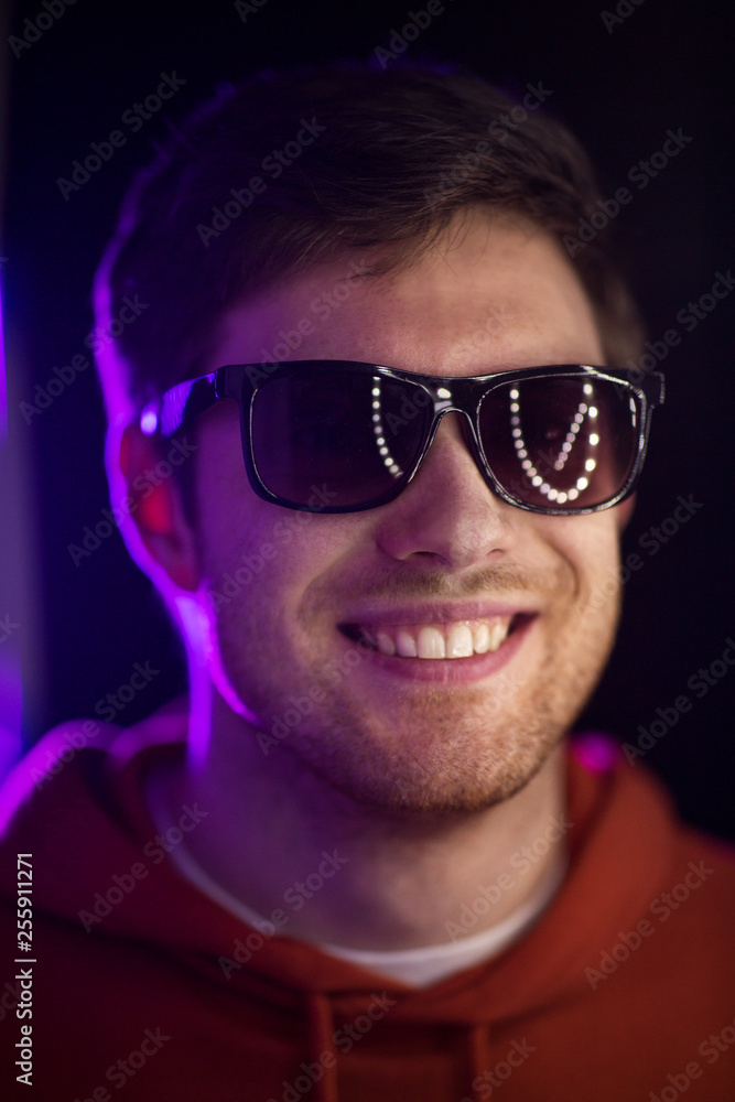 leisure, clubbing and nightlife concept - portrait of smiling young man in sunglasses at dark room over ultra violet neon lights of night club leisure, clubbing and nightlife concept - portrait of smiling young man in sunglasses at dark room over ultra violet neon lights of night club