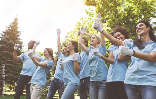 Group of happy volunteers celebrating success up in park photo