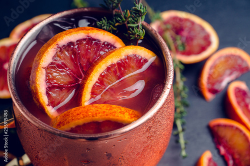 Red oranges cocktail in copper mug (variation of Moscow mule) on the wooden background. Selective focus. Shallow depth of field. photo