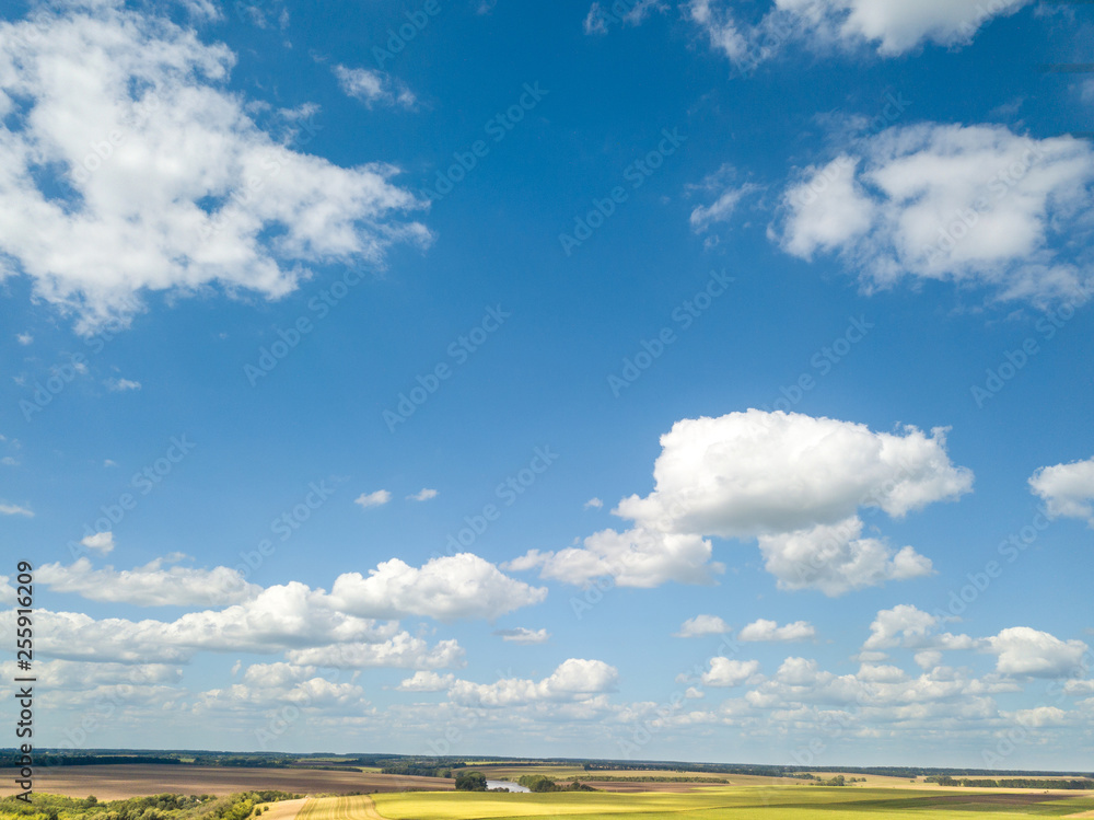 Cloudy aerial landscape with white clouds and fields on a blue sky background. Aerial view from drone. Cloudy aerial landscape with white clouds and fields on a blue sky background. Aerial view from drone.