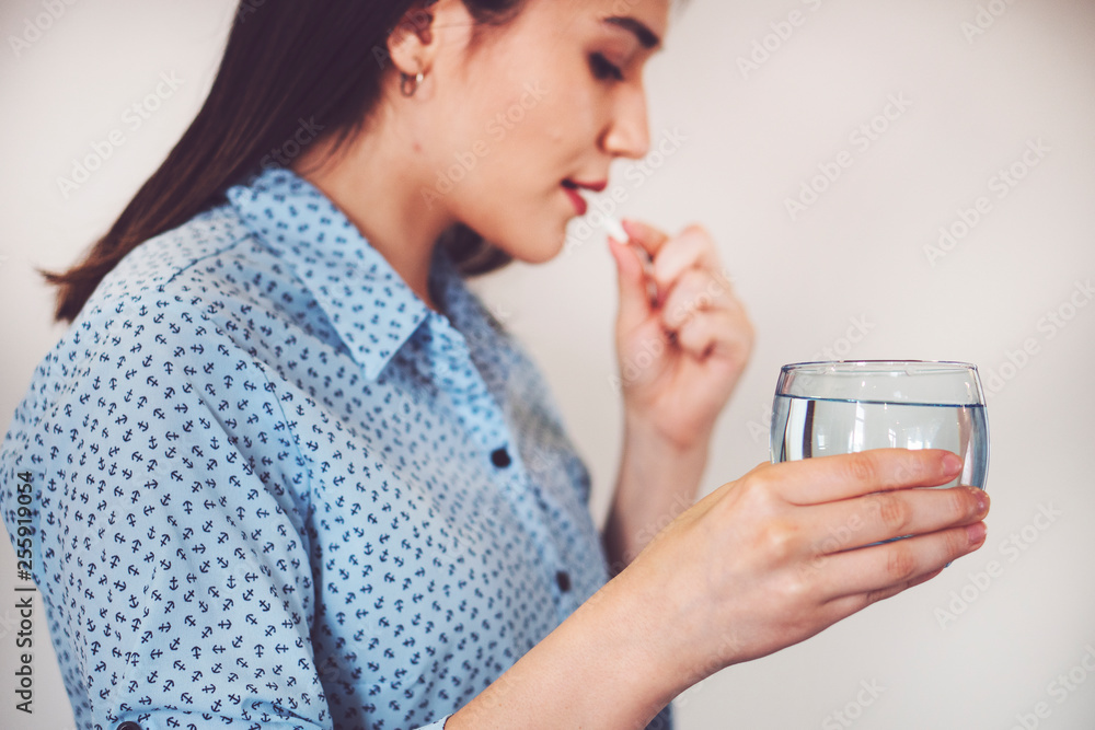 white pill and a glass of water in female hands white pill and a glass of water in female hands