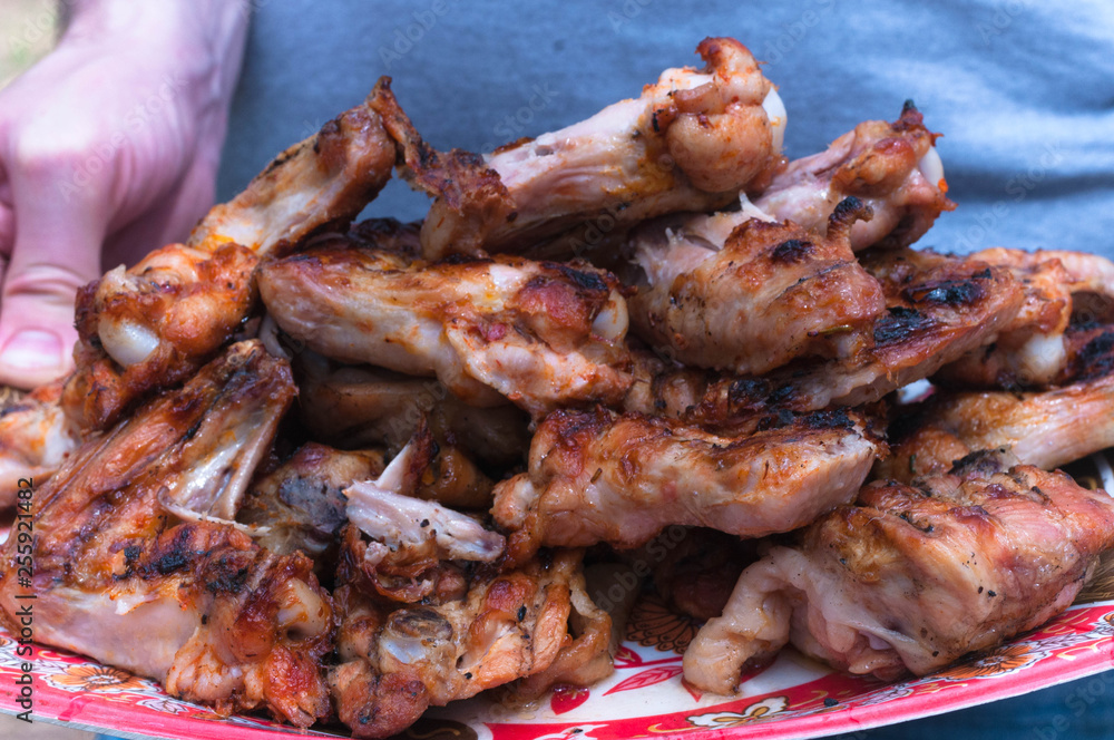 partial view of man holding plate with grilled chicken wings