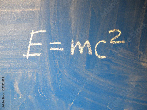 Naklejka Mathematical formula e=mc2 squared written on a blue, relatively dirty chalkboard by chalk.