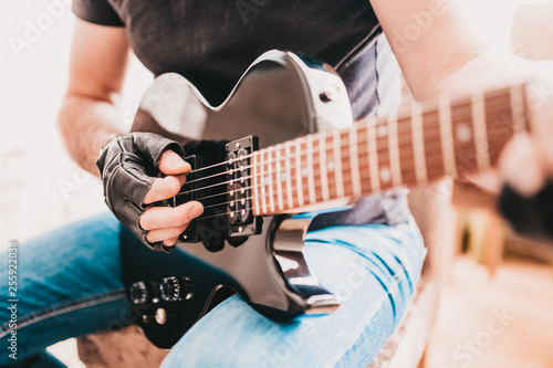Close up of rocker guitarist hands playing heavy riff on electric guitar