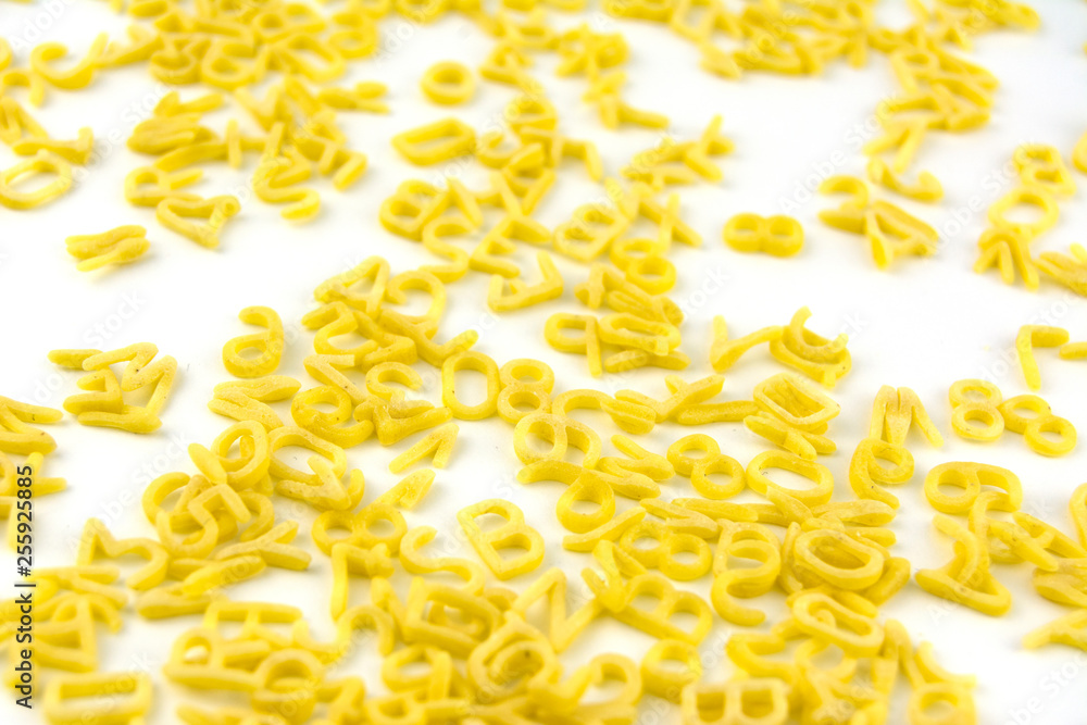 Pasta in the form of letters and numbers scattered on white Pasta in the form of letters and numbers scattered on white
