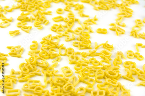 Pasta in the form of letters and numbers scattered on white