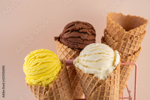 Assorted ice cream in sugar cones on pink background.
