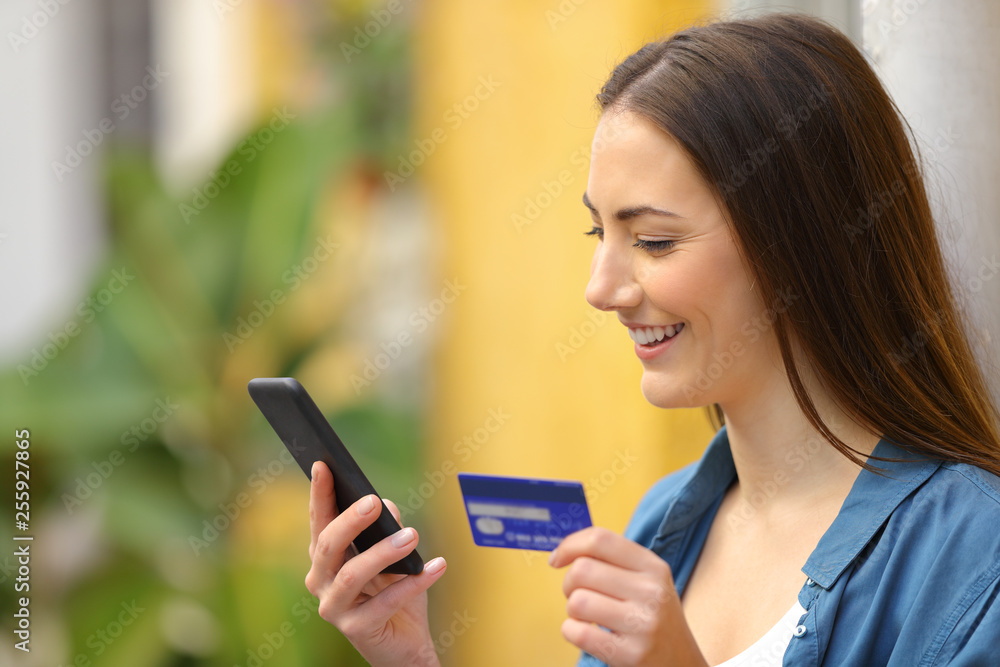 Happy woman paying online using credit card and phone Happy woman paying online using credit card and phone