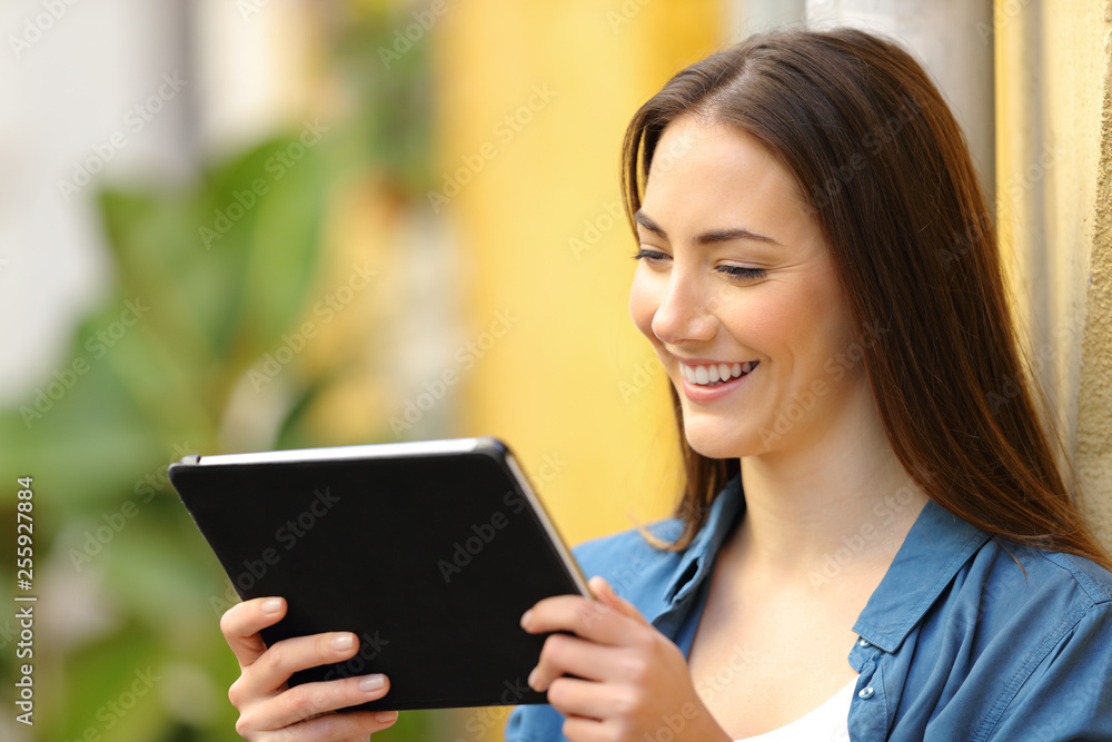 Happy woman watching media online on tablet in the street Happy woman watching media online on tablet in the street