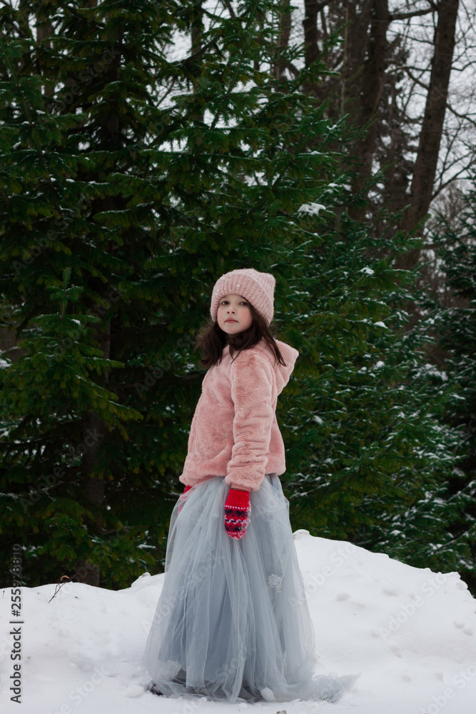 Girl child in pink coat at winter forest