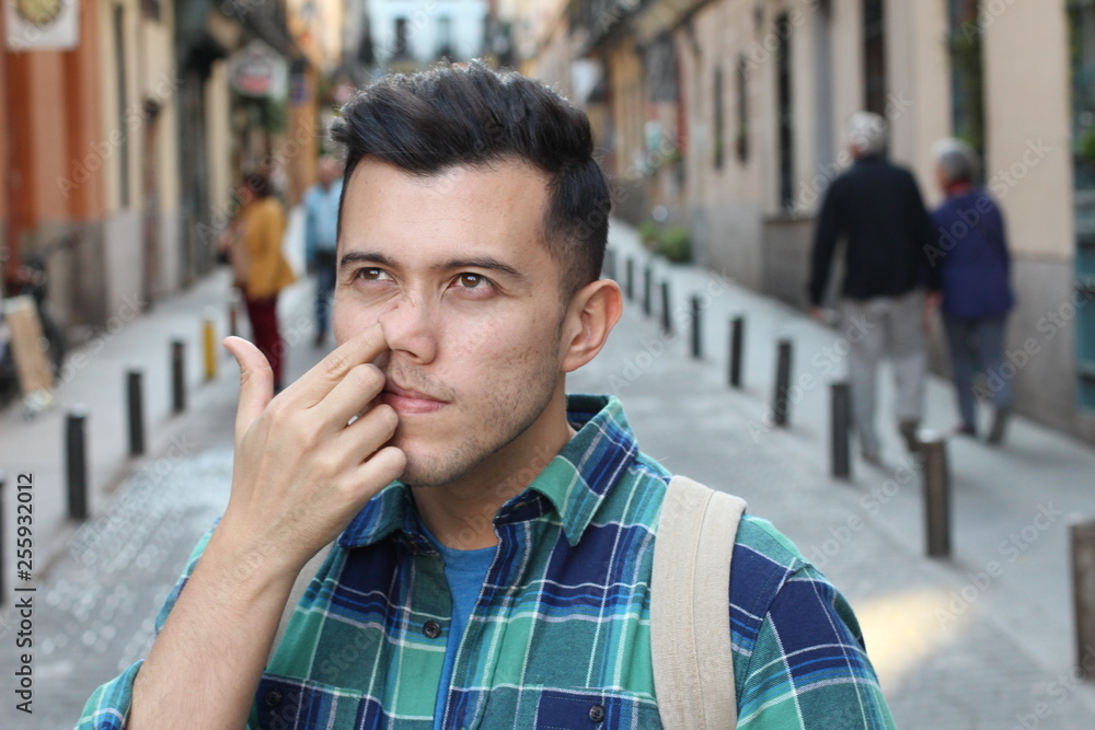 Young guy picking his nose in crowded place Young guy picking his nose in crowded place