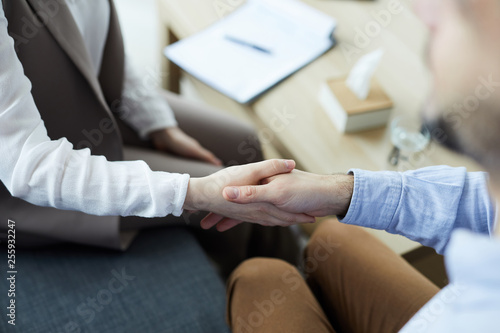 Young man shaking hand with counselor after conversation and discussion of his problems