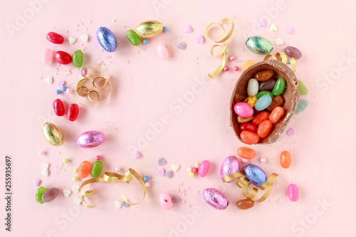 Chocolate Easter eggs and other sweets on pink background.