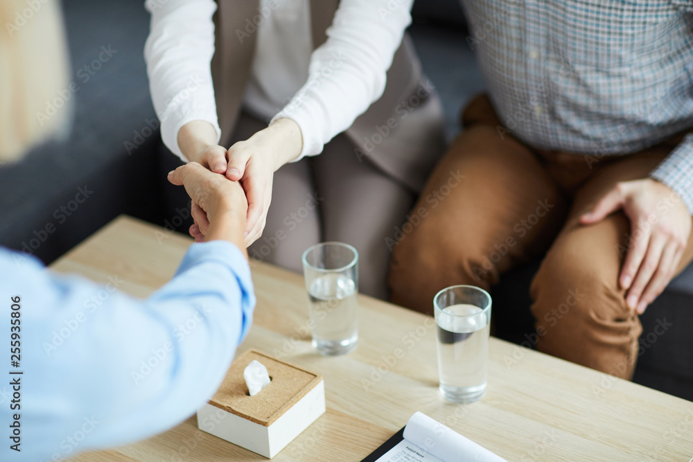 One of young patients shaking hand of counselor over table while being grateful for her advice One of young patients shaking hand of counselor over table while being grateful for her advice