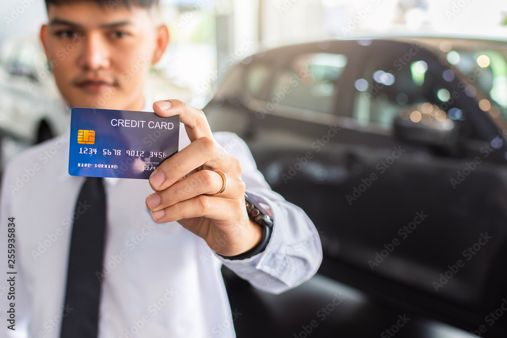 Asian man holding credit card for car blurred bokeh background e-shopping marketing digital, consumer purchase shopping internet online image Asian man holding credit card for car blurred bokeh background e-shopping marketing digital, consumer purchase shopping internet online image