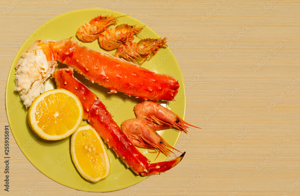 boiled king crab, shrimps in a plate on a wooden background boiled king crab, shrimps in a plate on a wooden background