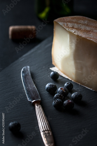 cheese board with hard mature cheese, antique knife and blueberries. Selective focus. photo