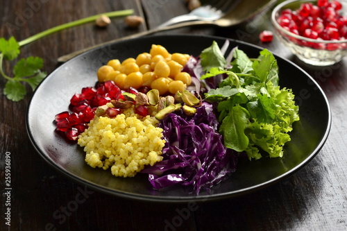 Healthy vegetarian salad. Millet, chickpea, pomegranate seeds, red cabbage, onions, arugula. Buddha bowl.