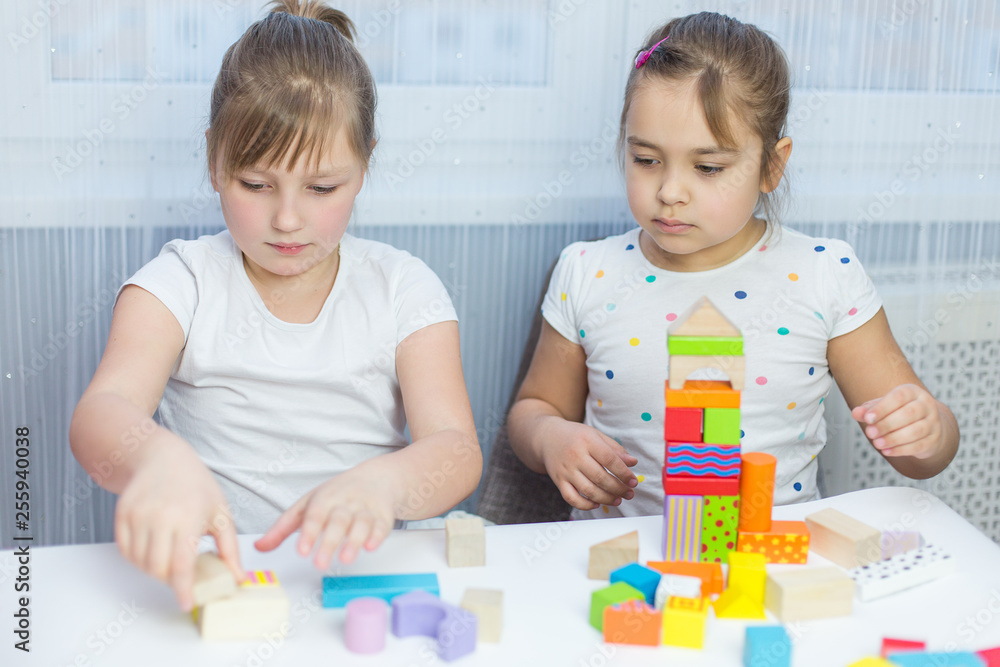 Obraz premium Children play with an educational toy on table in the children's room. Two kids playing with colorful blocks. Kindergarten educational games