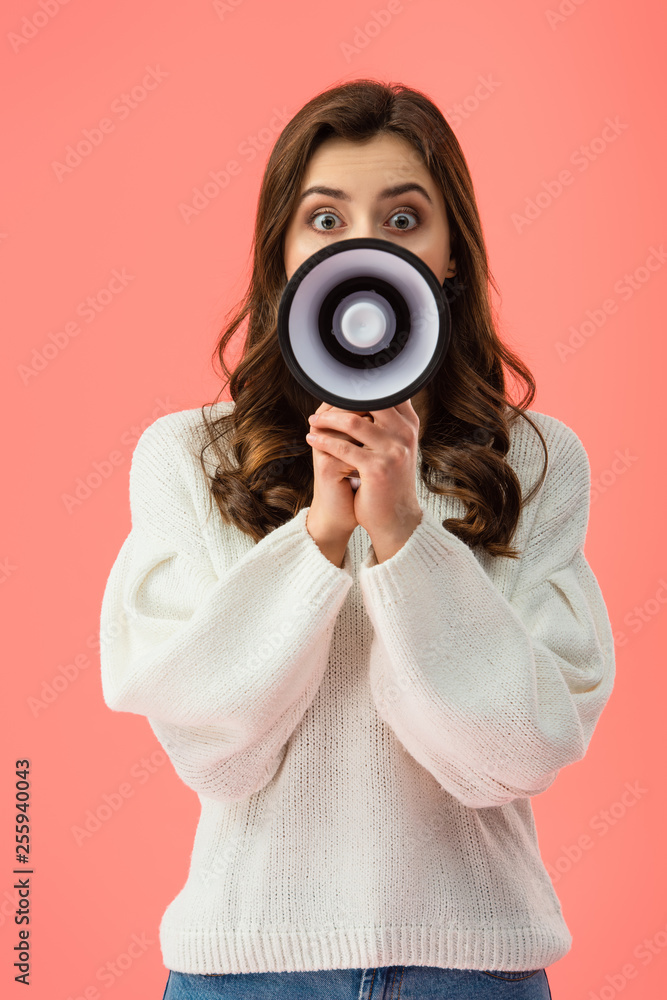 Fototapeta premium brunette woman in white sweater screaming in megaphone isolated on pink