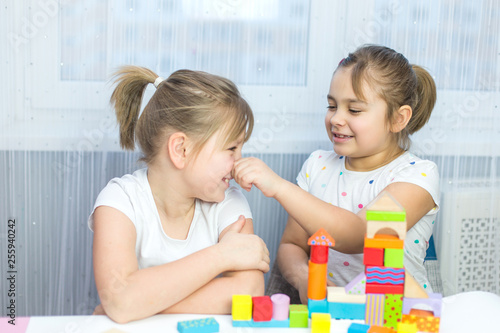 Children play with an educational toy on table in the children's room. Two kids playing with colorful blocks. Kindergarten educational games
