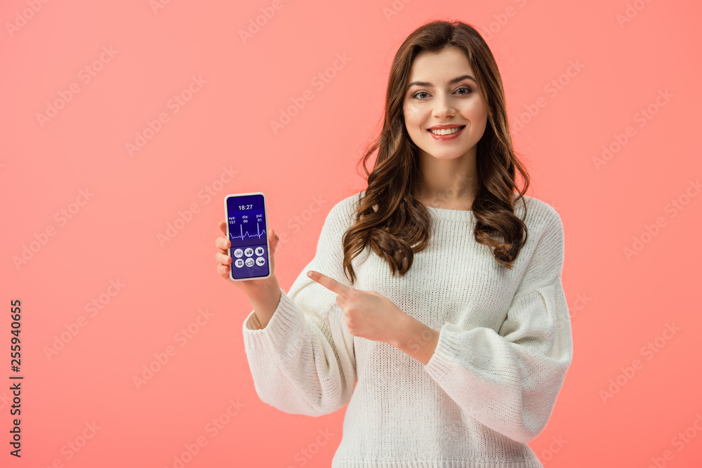 woman in white sweater pointing with finger at smartphone with health app on screen isolated on pink woman in white sweater pointing with finger at smartphone with health app on screen isolated on pink