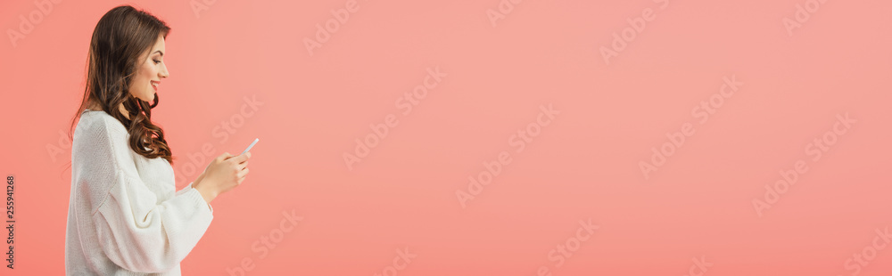 panoramic shot of smiling and attractive woman in white sweater holding smartphone isolated on pink panoramic shot of smiling and attractive woman in white sweater holding smartphone isolated on pink