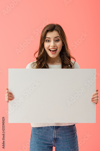 happy and beautiful woman holding empty board with copy space isolated on pink