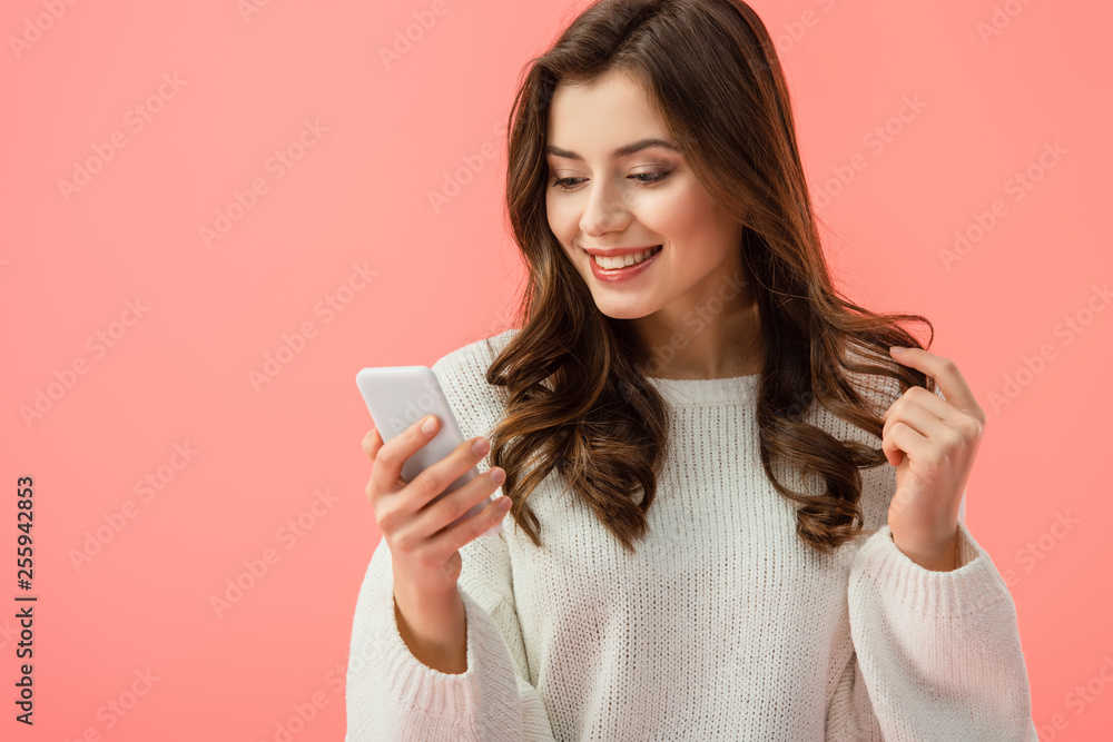 smiling and attractive woman in white sweater holding smartphone isolated on pink smiling and attractive woman in white sweater holding smartphone isolated on pink