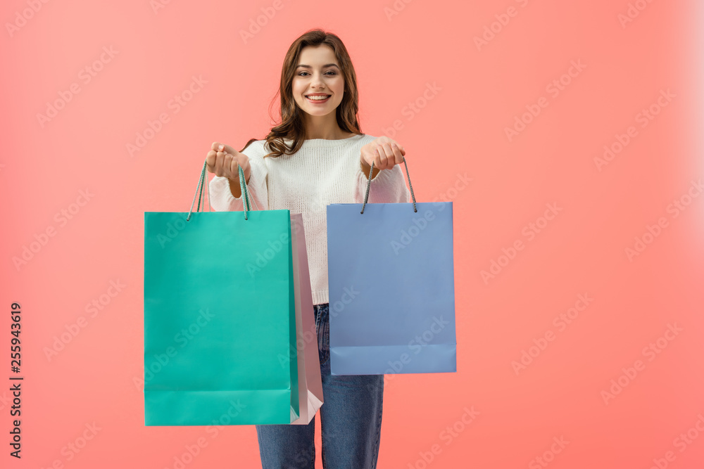 smiling woman in white sweater and jeans holding shopping bags isolated on pink smiling woman in white sweater and jeans holding shopping bags isolated on pink
