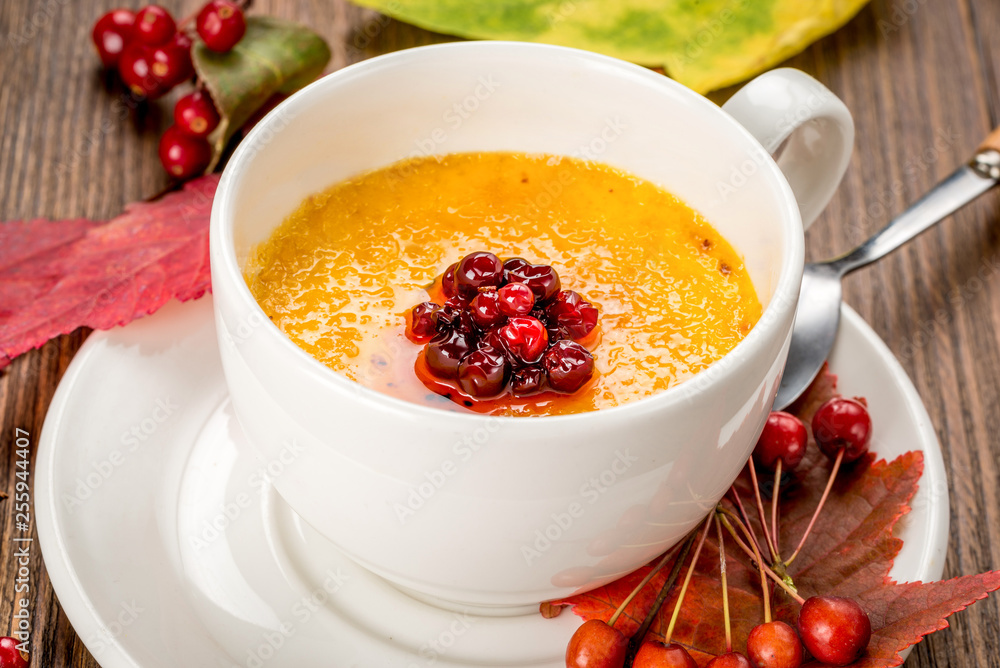 Yellow soup decorated with rowan in a white plate Yellow soup decorated with rowan in a white plate