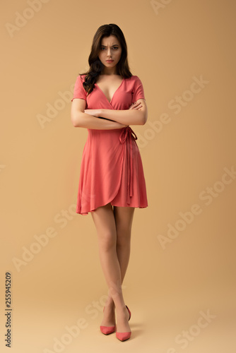 Foto attractive woman standing with crossed arms and crossed legs on brown background