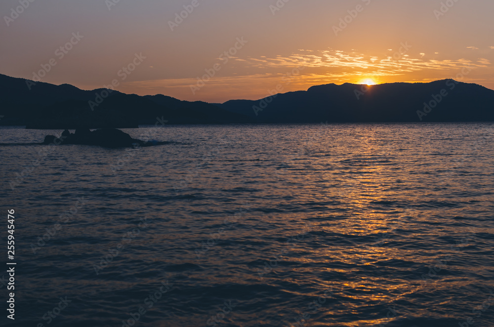 Dramatic Sunset over Mountain silhouettes under red sky and blue Sea on fethiye Mediterranean Turkey