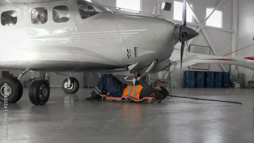 Woman repairing airplane, lying under it Woman repairing airplane, lying under it