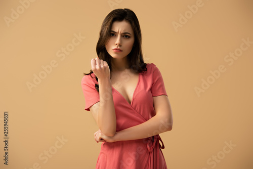 confused brunette girl looking at camera isolated on brown