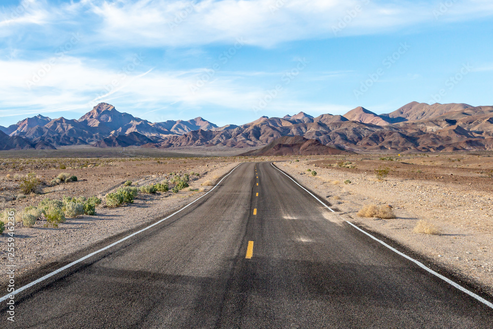A road in Death Valley National Park, California, with rugged mountains in the distance A road in Death Valley National Park, California, with rugged mountains in the distance