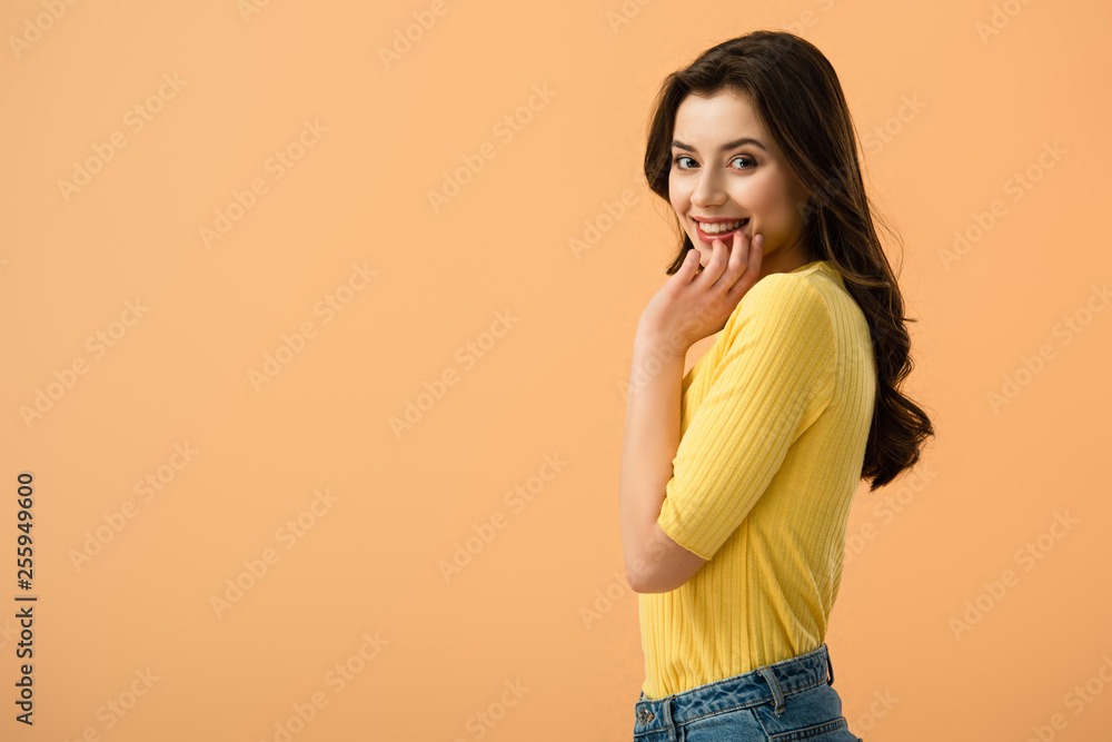 cheerful young woman smiling while standing isolated on orange cheerful young woman smiling while standing isolated on orange