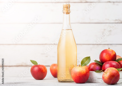 Fototapeta Naklejka Na Ścianę i Meble -  Bottle of homemade organic apple cider with fresh apples in box on wooden background with sun light