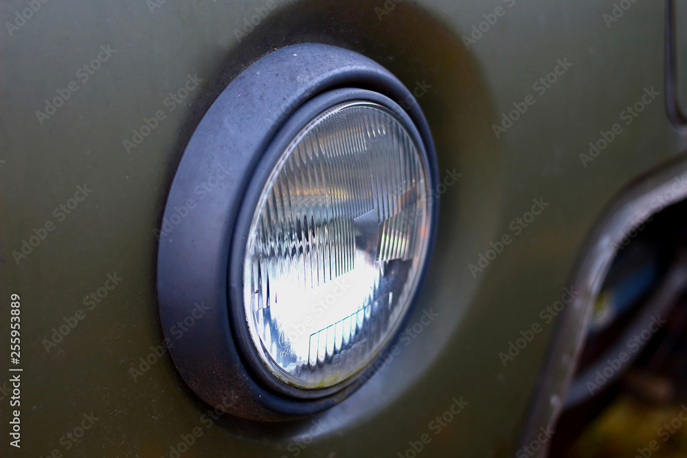 Glass headlight of an old retro russian truck SUV all-terrain khaki colour Glass headlight of an old retro russian truck SUV all-terrain khaki colour