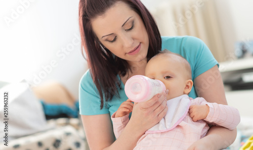 Mother feeding baby girl with bottle