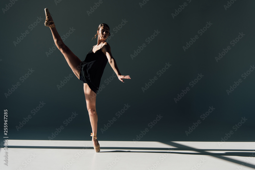 attractive ballerina dancing in black dress and pointe shoes